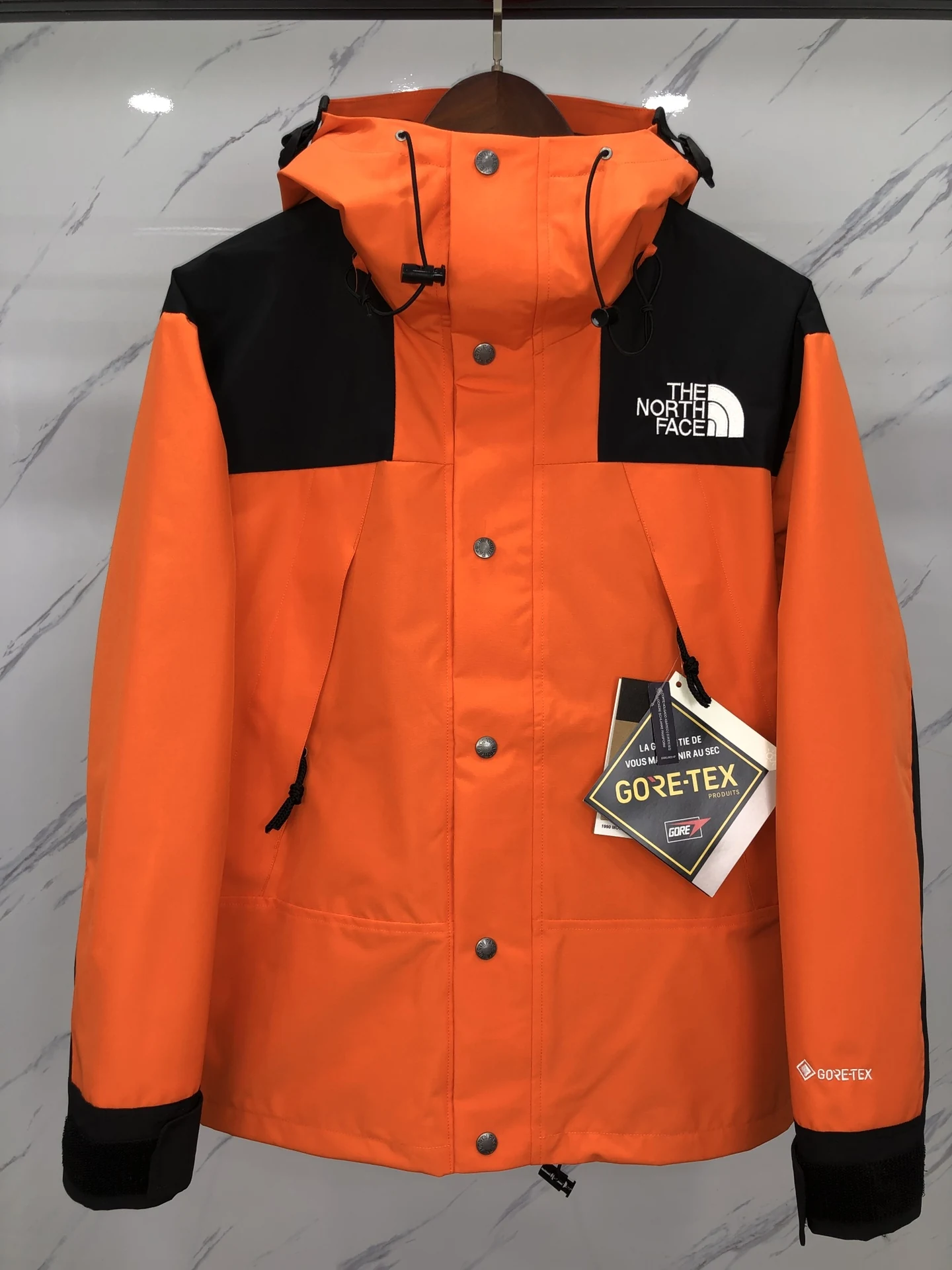 Orange technical mountain jacket with closed storm flap