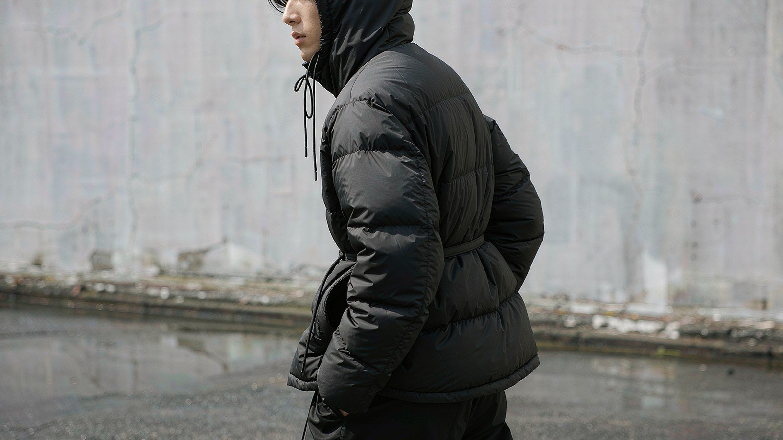 Model wearing a black matte nylon short down jacket on a city street